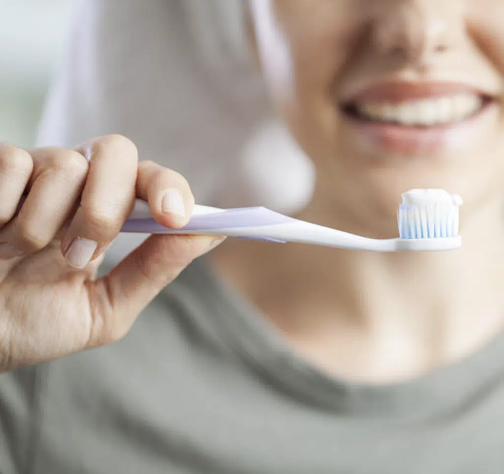 Woman preparing to brush demonstrating recommended toothpaste for braces